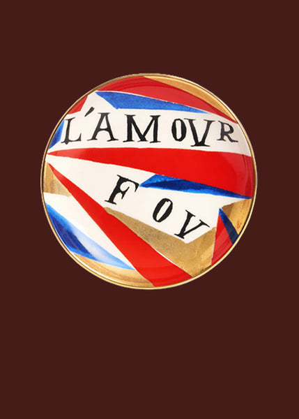 The words "L'amour Fou" are hand painted on this red, gold, blue and white hand made round ceramic plate.  The colours are organised in an abstract arrangement, with a 24 carat gold finish.